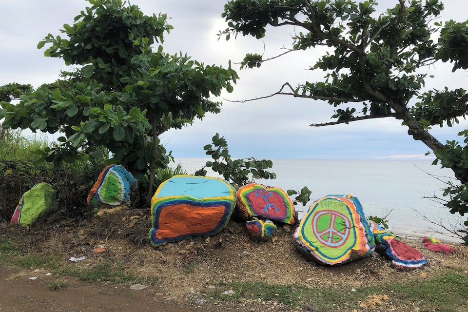 Colorful painted rocks by a coastal path.