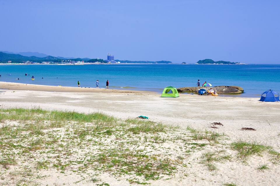 Uma praia com tendas e pessoas.