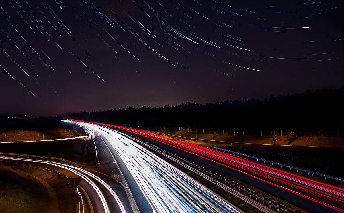 A nighttime highway with light trails from moving vehicles.