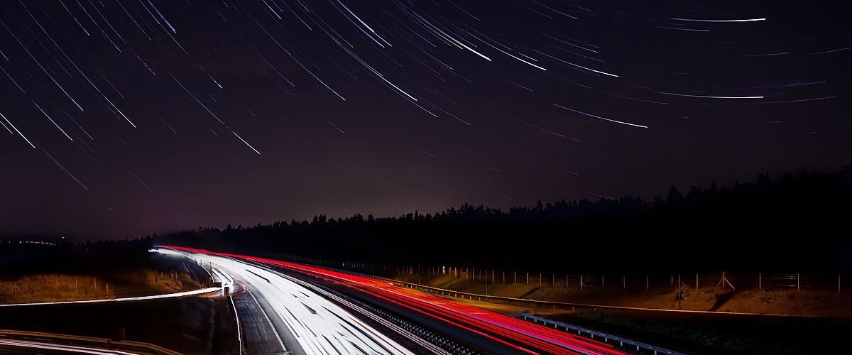 A nighttime highway with light trails from moving vehicles.