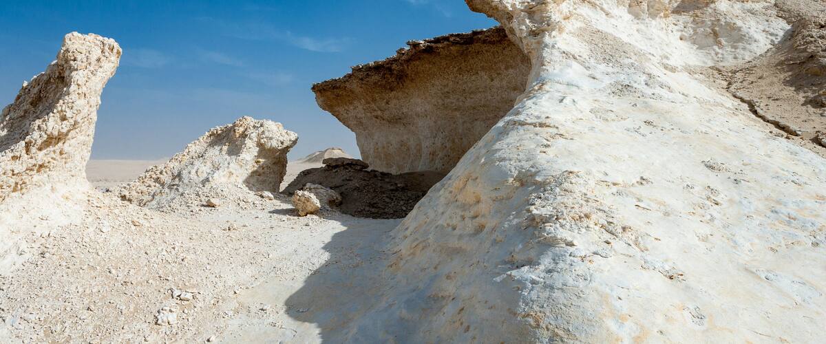 A desert landscape with prominent rock formations and a clear blue sky.