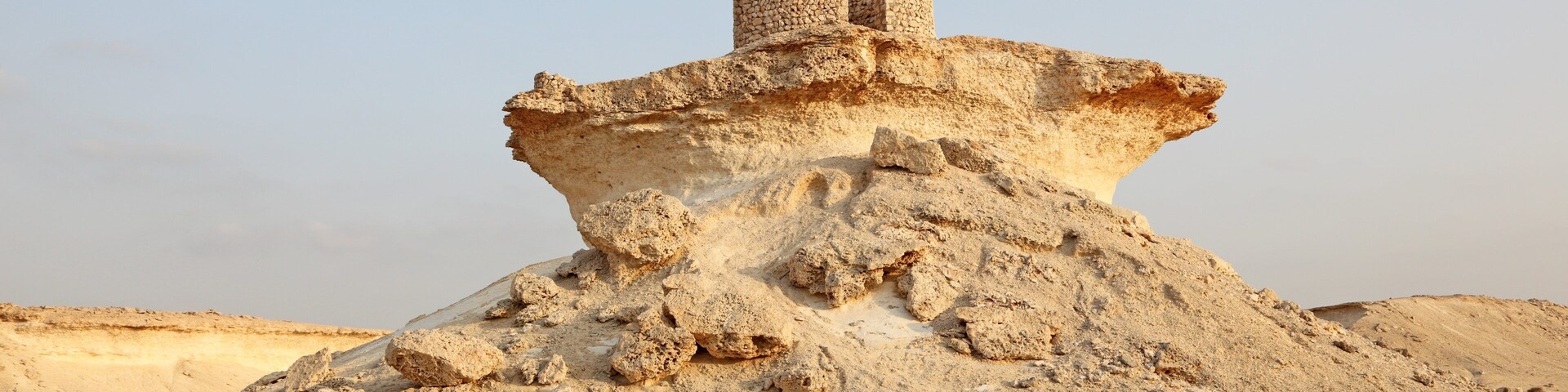 Una duna de arena extensa con una construcción de piedra en su cima.