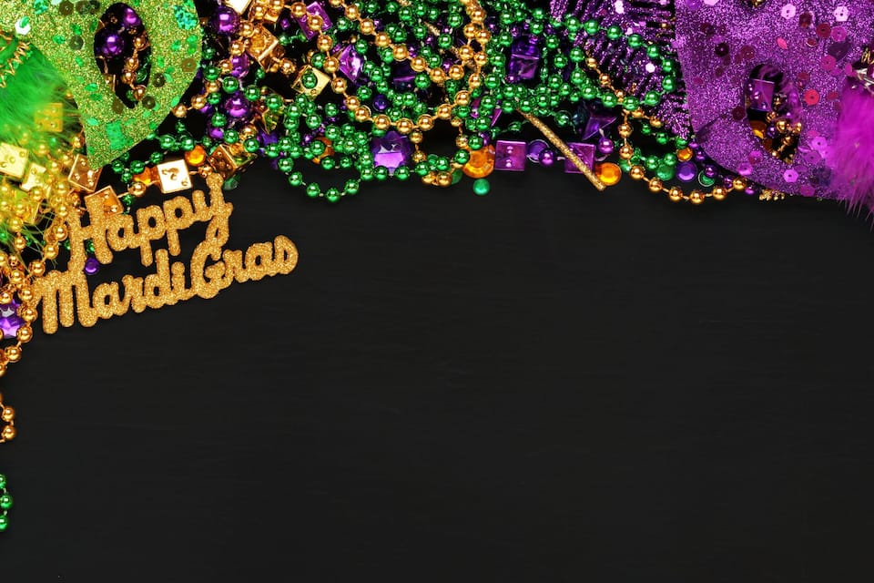 A Mardi Gras decoration with beads, feathers, and the text "Happy Mardi Gras".