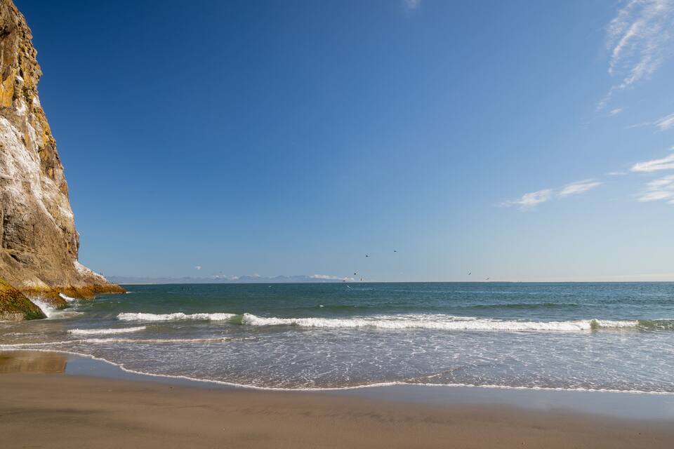 Una playa con un acantilado rocoso y olas.