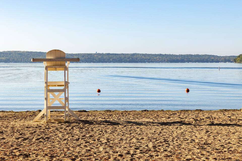 A lifeguard tower on a sandy beach with calm water and buoys.
