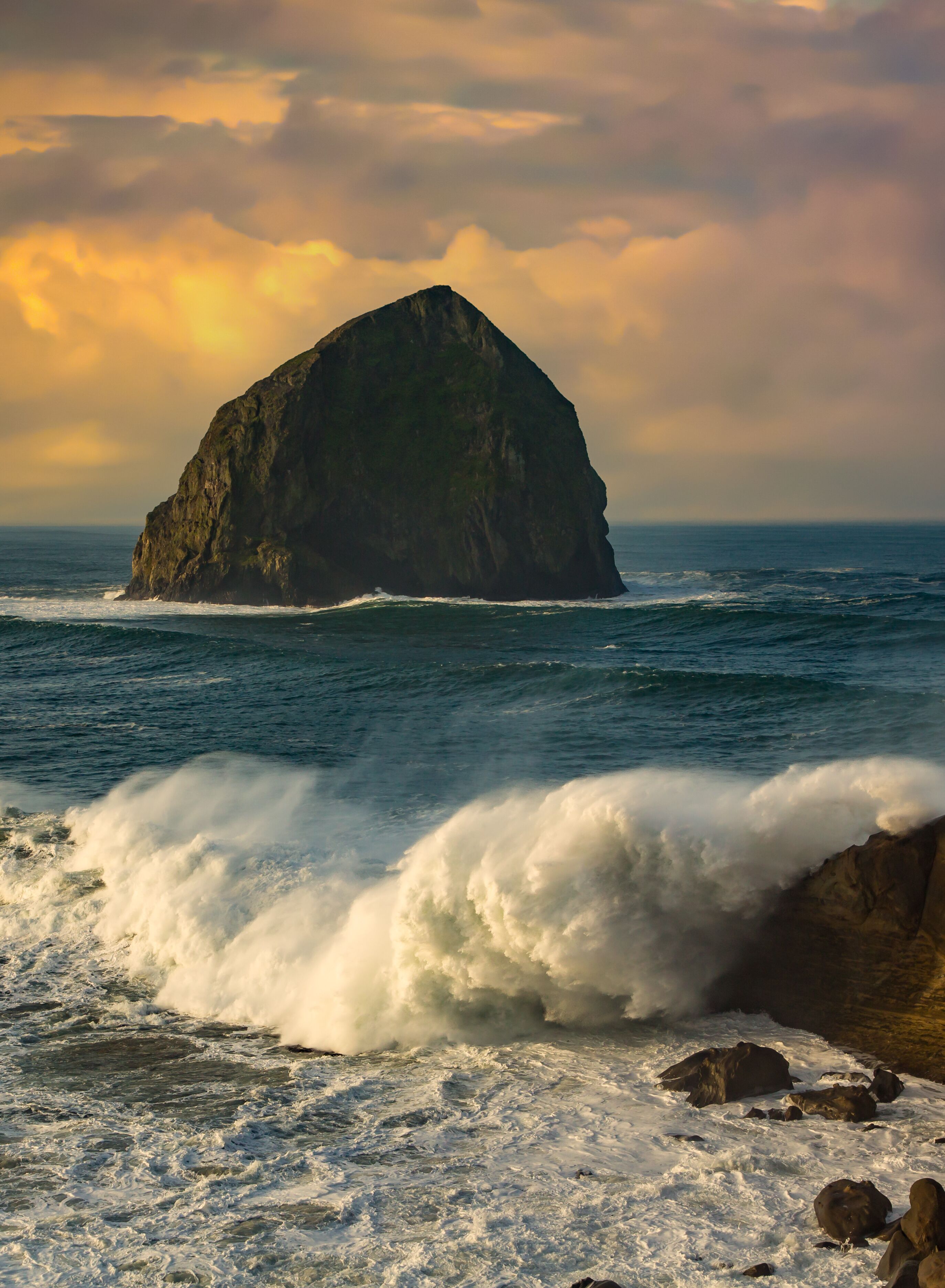 Haystack rock and a huge wave crashing on the rocks at Pacific City on the Oregon coast.