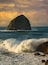 A rugged coastline with a prominent rock formation surrounded by turbulent ocean waves.
