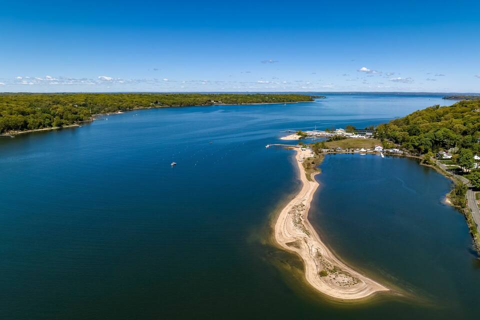 A large body of water with a narrow, sandy beach and a small island with buildings.