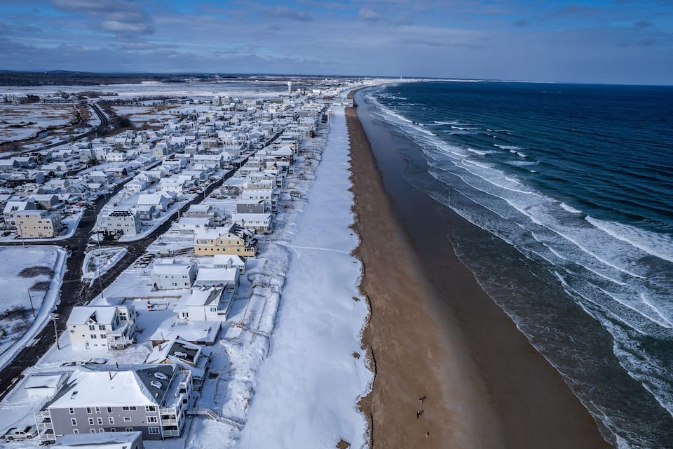 Een kustplaats met een strand en gebouwen bedekt met sneeuw.