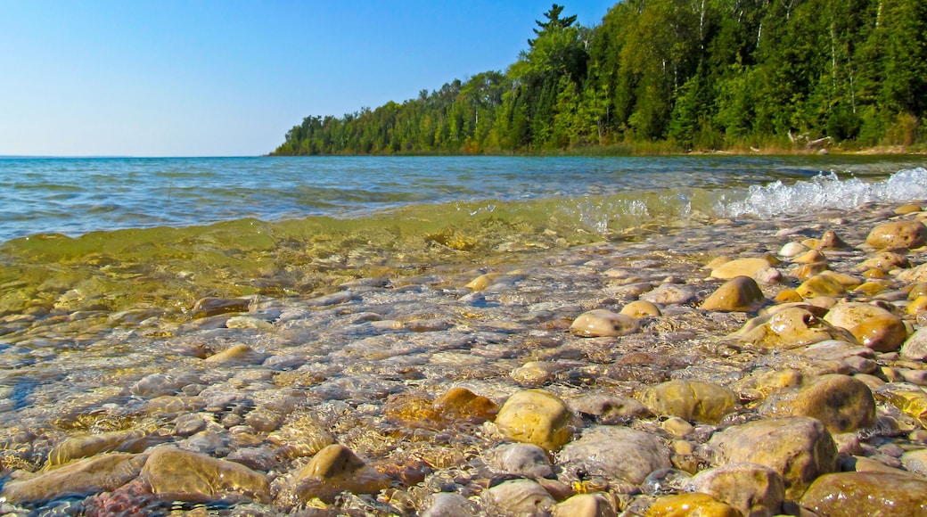 Transparent water and pebbles on the beach coast. Summer coastline landscape on sunny day on Lake Michigan, North America.
