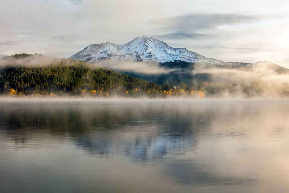 Montanha nevada, floresta e lago calmo.