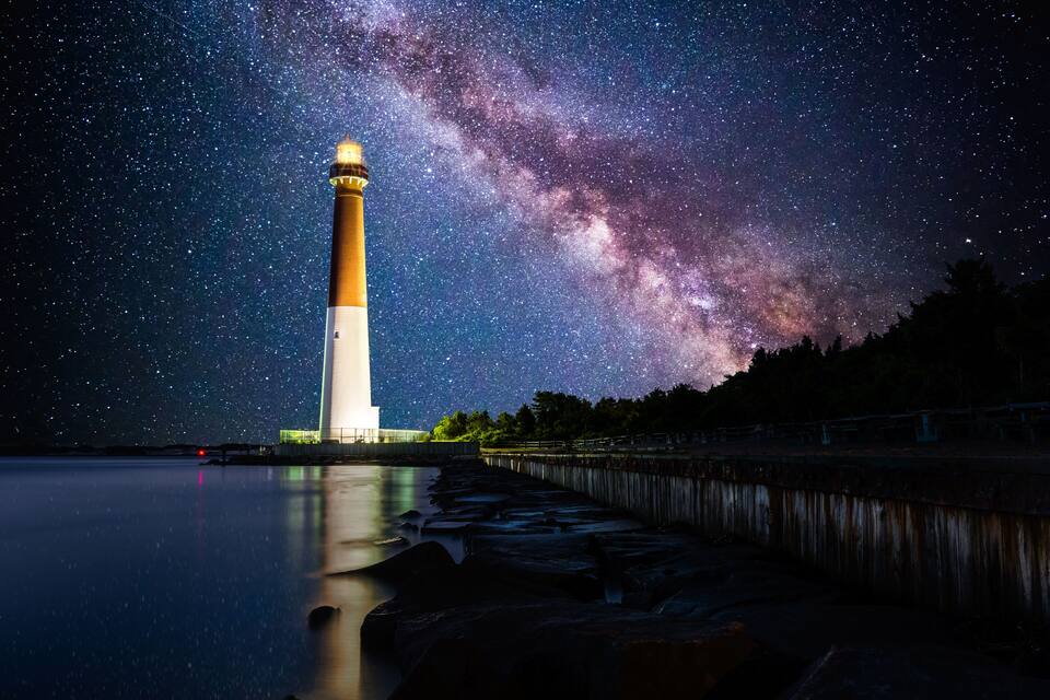 A lighthouse at night with a starry sky and the Milky Way.