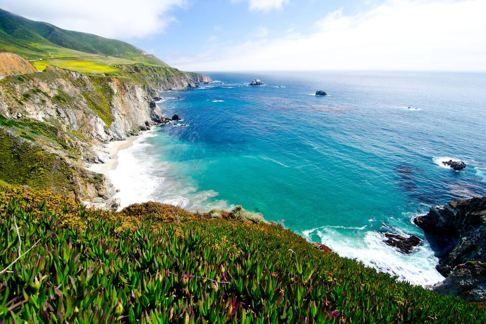 A coastal landscape with cliffs, a beach, and the ocean.