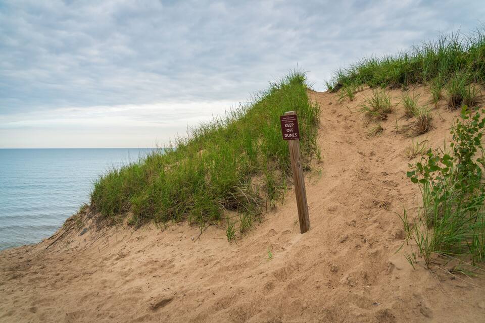A sandy beach with a sign that reads "KEEP OFF DUNES."