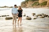 Beautiful pregnant couple walking along the coastal beach shore