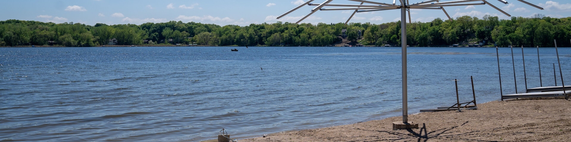 Beach umbrella, empty, sits on a lonely sandy beach on Clifton French Regional Park in Plymouth Minnesota