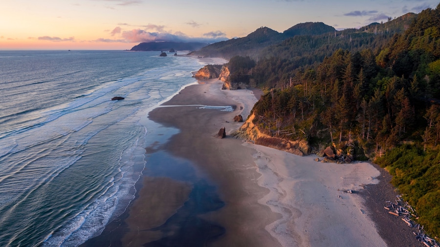 Aerial View of Arch Cape, Oregon. Sunset along the Oregon coast near Cannon Beach features white sand beaches with fir and cedar forests as far as the eye can see.
