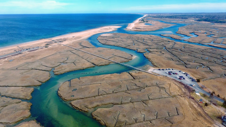 A coastal landscape with a winding river, a bridge, and a parking area.