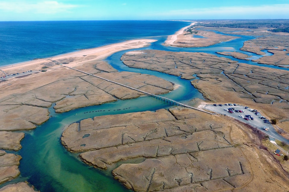 Een kustlandschap met een kronkelende rivier, een brug en een parkeerplaats.