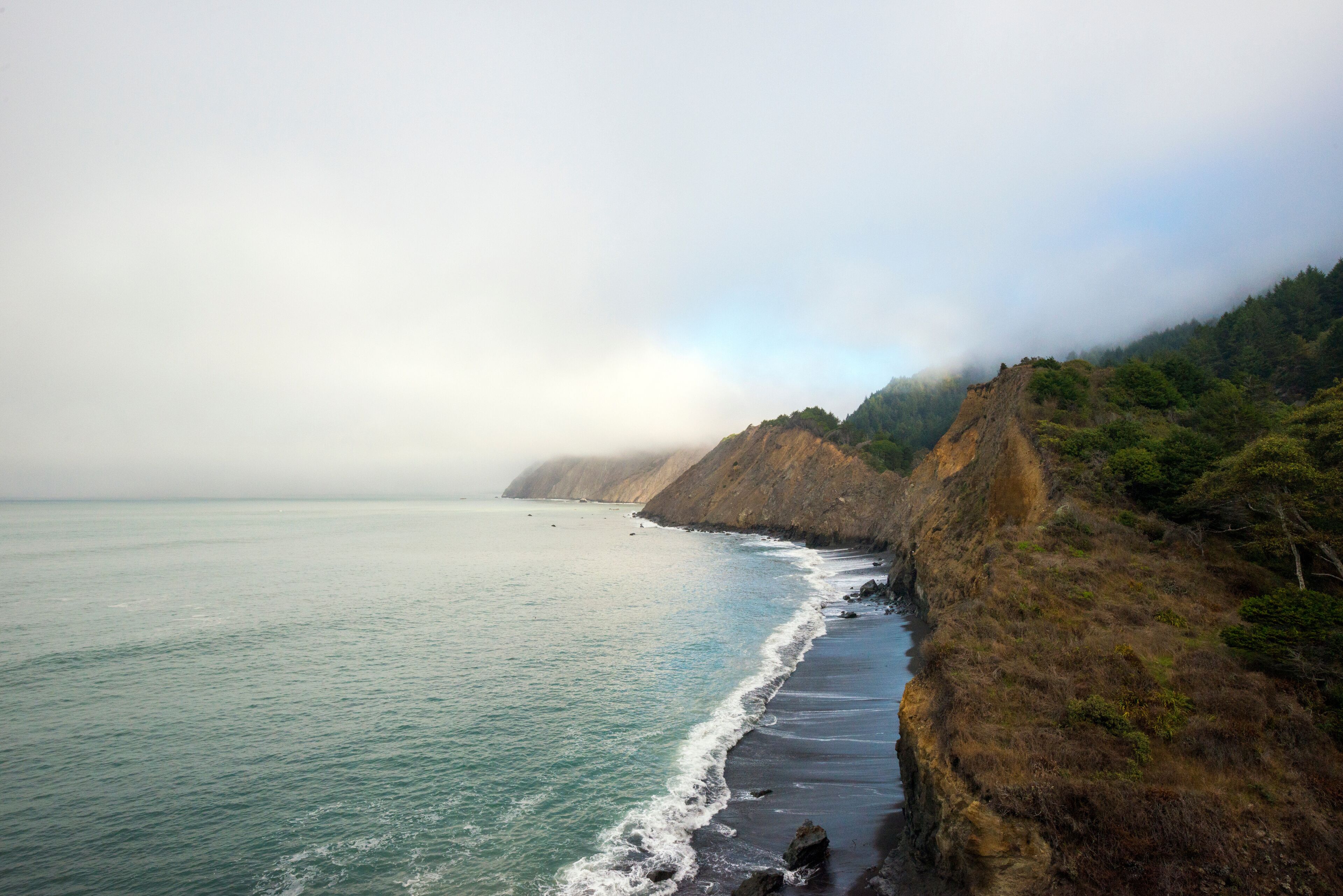 Looking north down the rugged foggy coastline of the Lost Coast from Jones Beach Camp towards Point No Pass on the Lost Coast Trail in Sinkyone Wilderness State Park in Northern California.