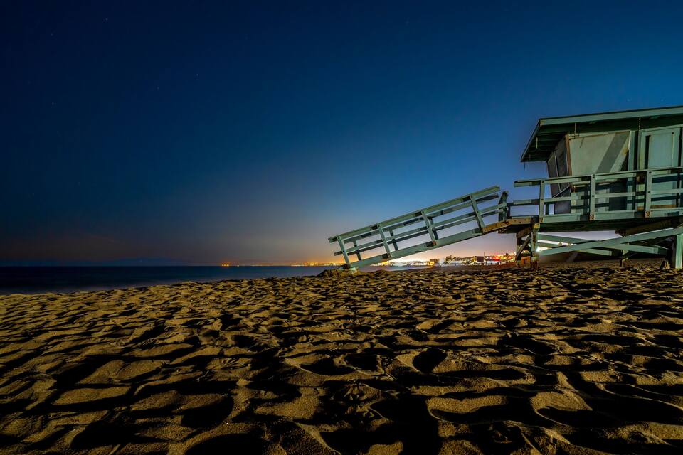 Une plage au crépuscule, avec une tour de surveillance des sauveteurs et l’océan en arrière-plan.
