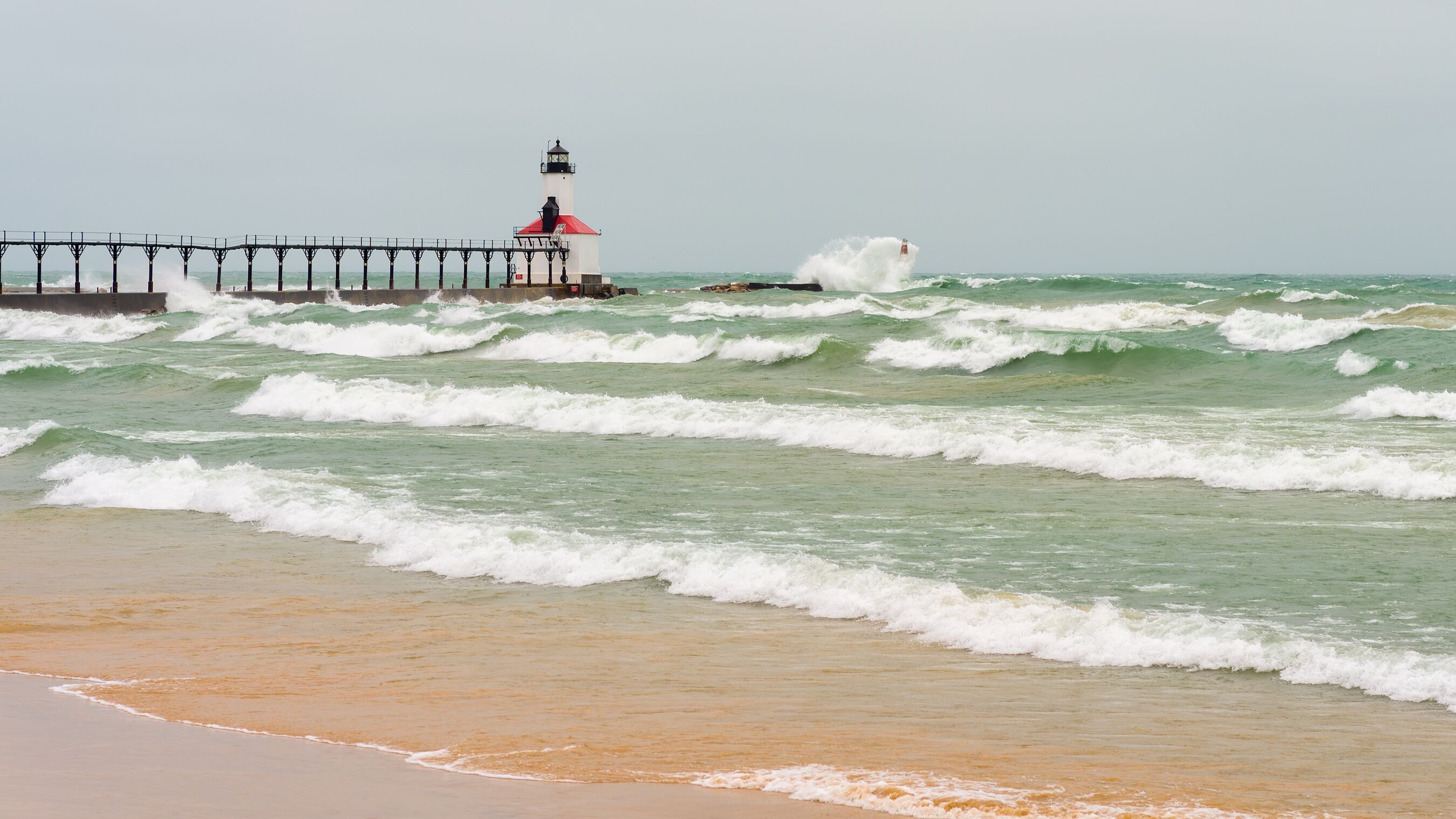 Lake Michigan waves crash against the East Pierhead Outer Lighthouse and catwalk, in Michigan City, Indiana.