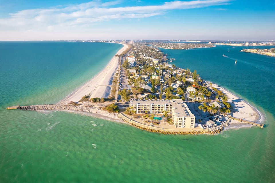 An aerial view of a coastal resort with a beach, water, and a hotel.