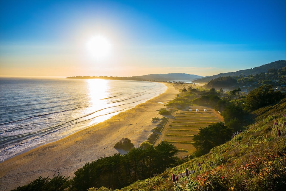 A coastal landscape with a beach, agricultural fields, and a hilly terrain.
