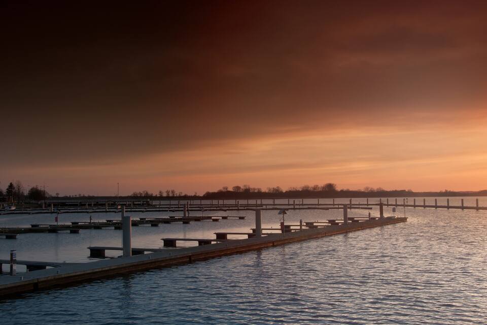A waterfront with docks and a sunset sky.