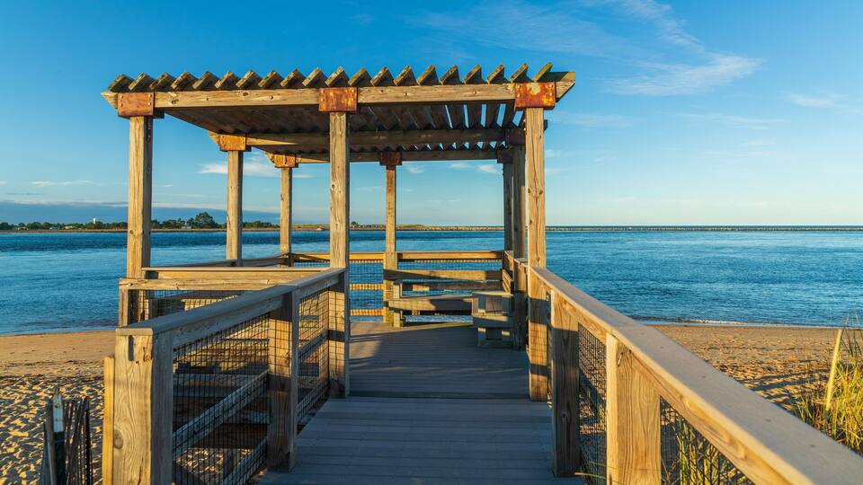 A wooden pier leading to a gazebo by a calm body of water.