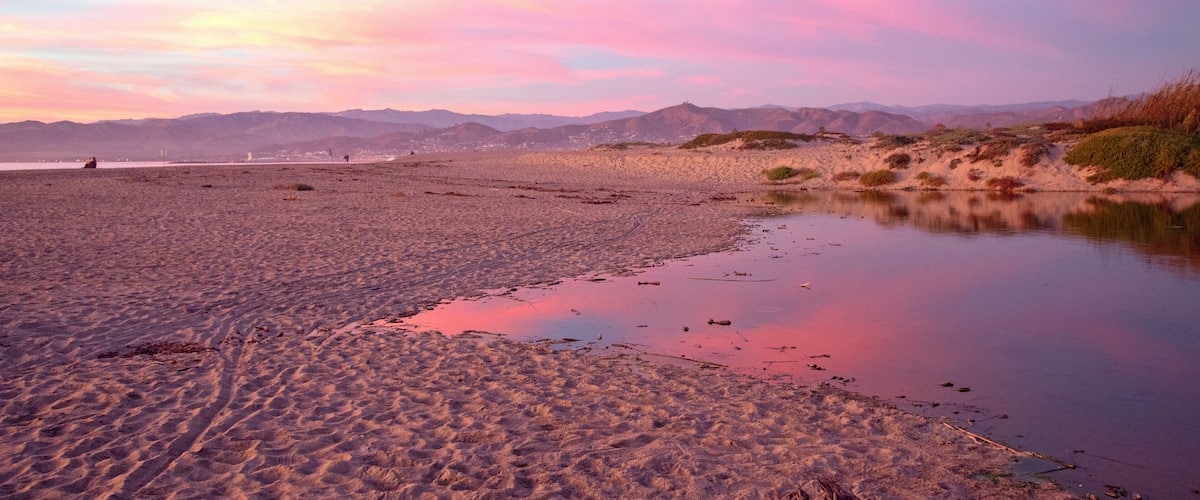 Pink sunset cloud reflection over Santa Clara river seaside marsh at Ventura beach in California United States