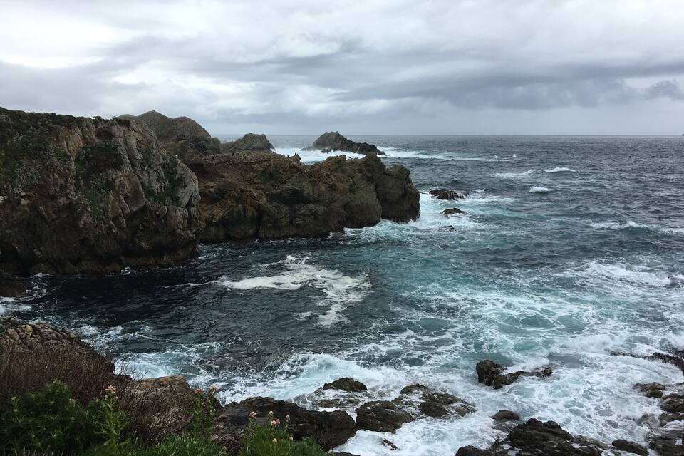 A rugged coastline with rocky cliffs and turbulent sea waves.