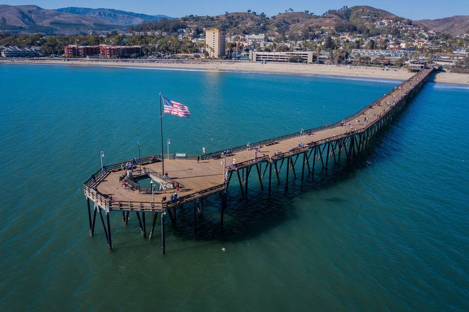 A pier extending into a clear blue body of water with an American flag at the end.