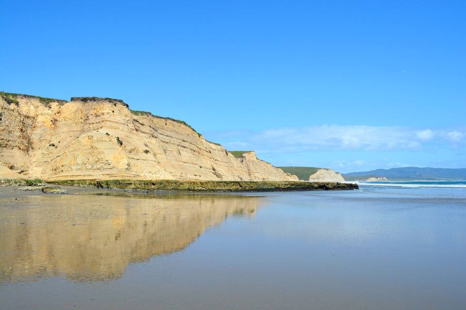 A coastal landscape with cliffs and calm waters reflecting the sky.