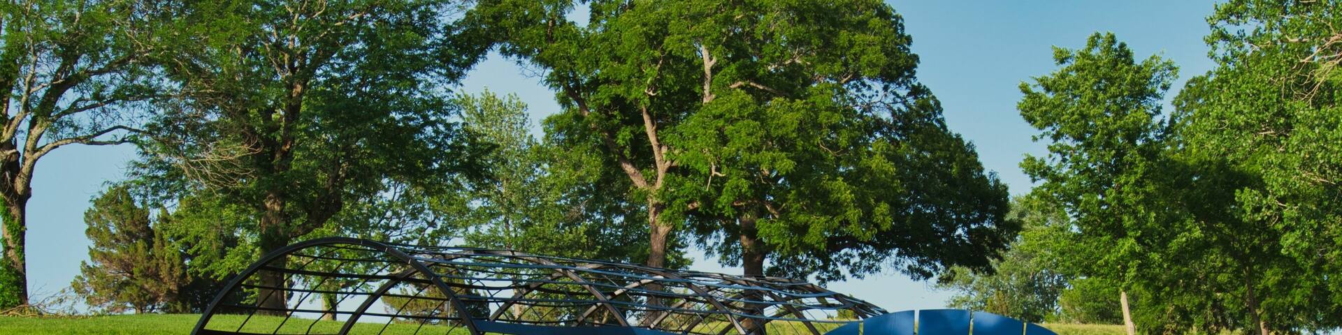 Blue wooden lawn chair near the splash pad in the green field at Olathe Lake