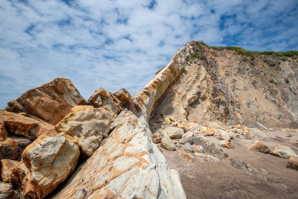 Paisagem costeira rochosa com grandes pedras e um penhasco íngreme.