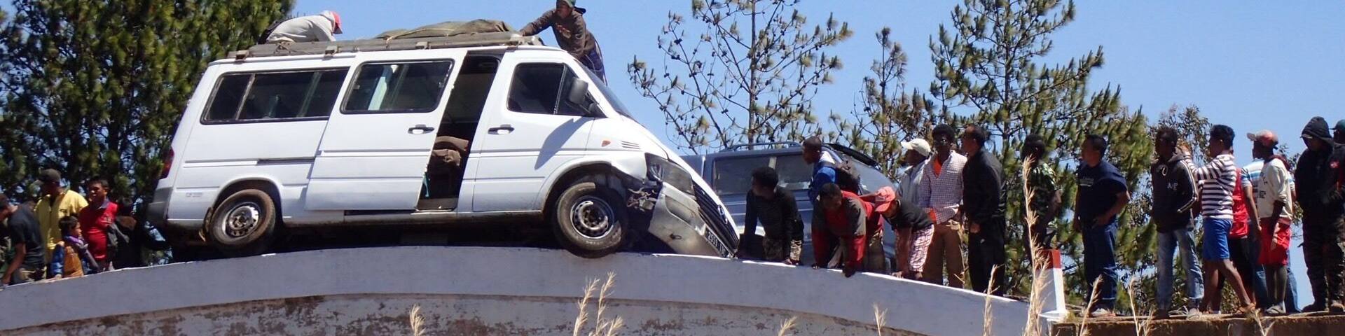 A white van parked on a bridge with people gathered around it.