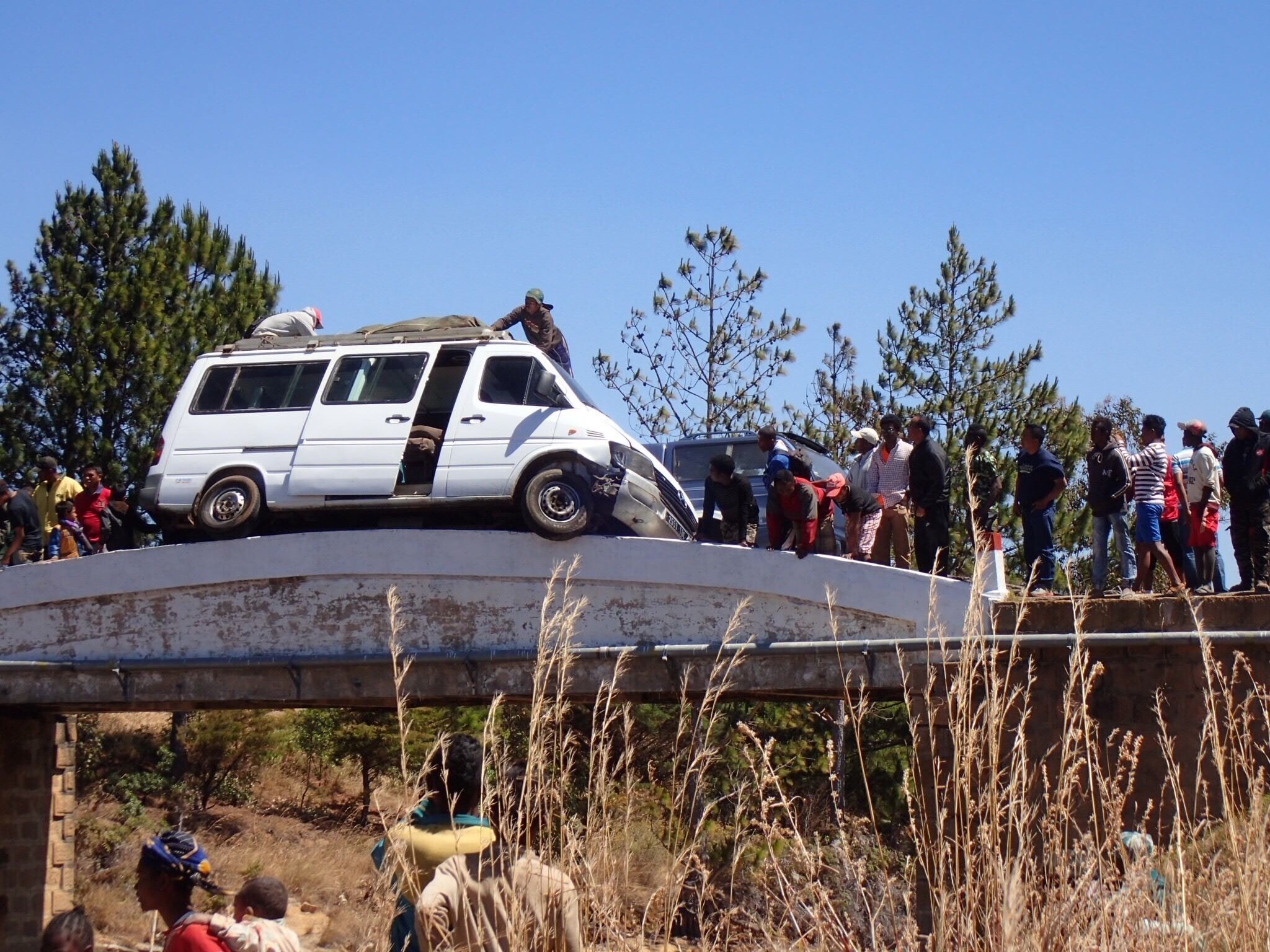 A white van parked on a bridge with people gathered around it.