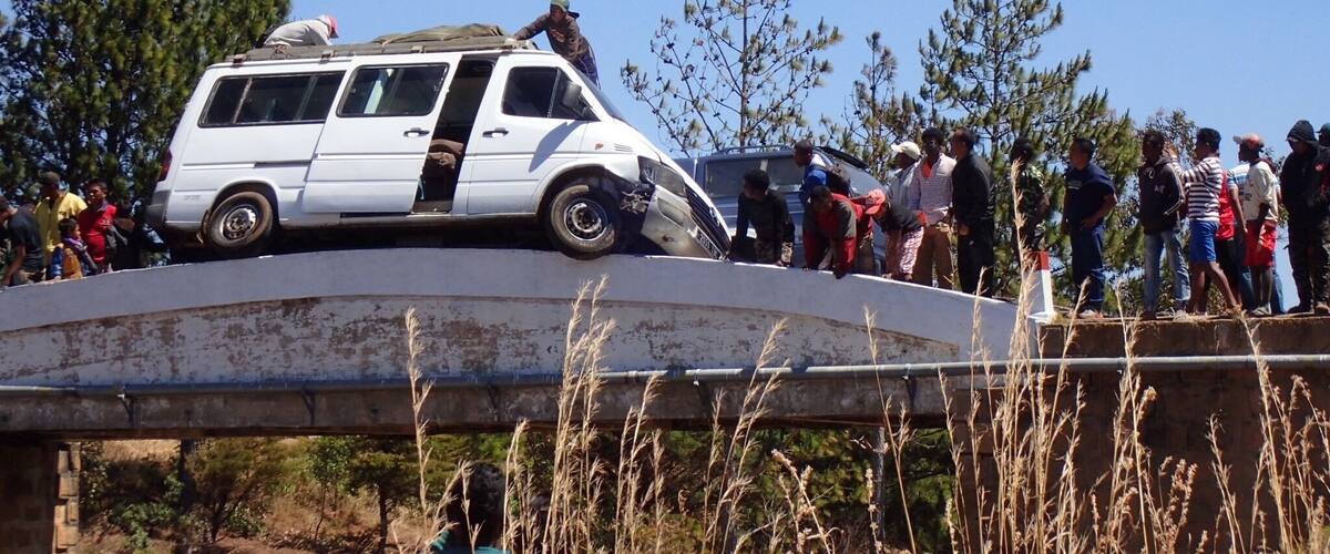 A white van parked on a bridge with people gathered around it.