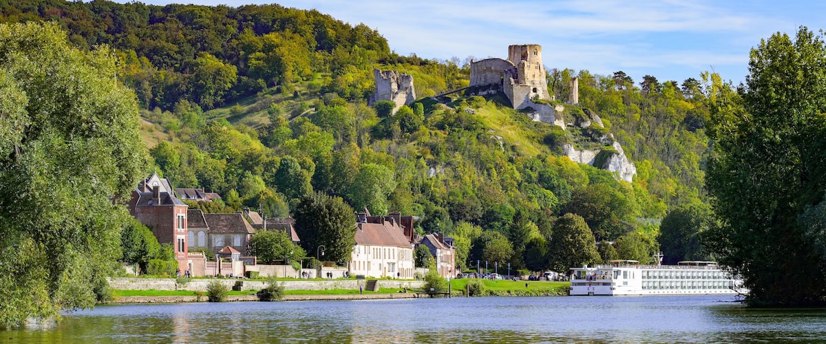 A historic castle on a hill, a river, and a boat.