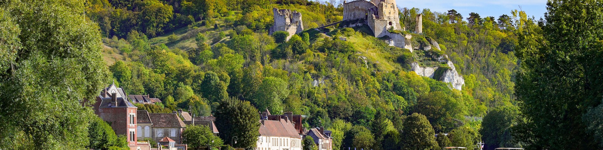 Un castillo histórico en una colina, un río y una barca.