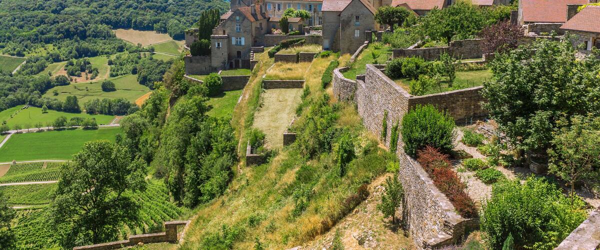 A historic village with stone buildings, a church, and terraced vineyards.