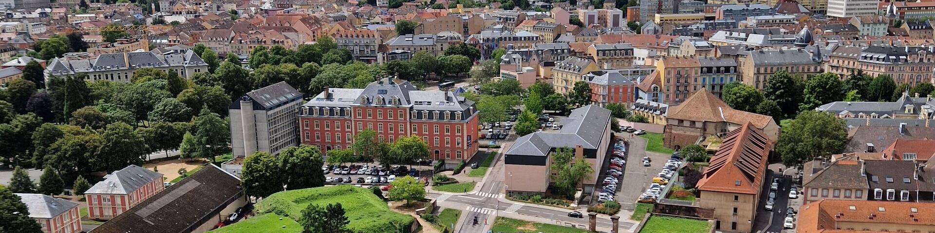Vue plongeante sur la ville de Belfort, avec un grand parking et des bĂątiments historiques