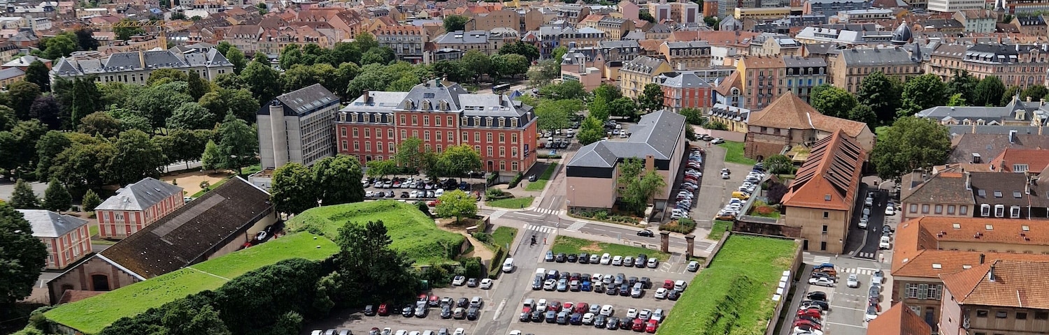Vue plongeante sur la ville de Belfort, avec un grand parking et des bâtiments historiques