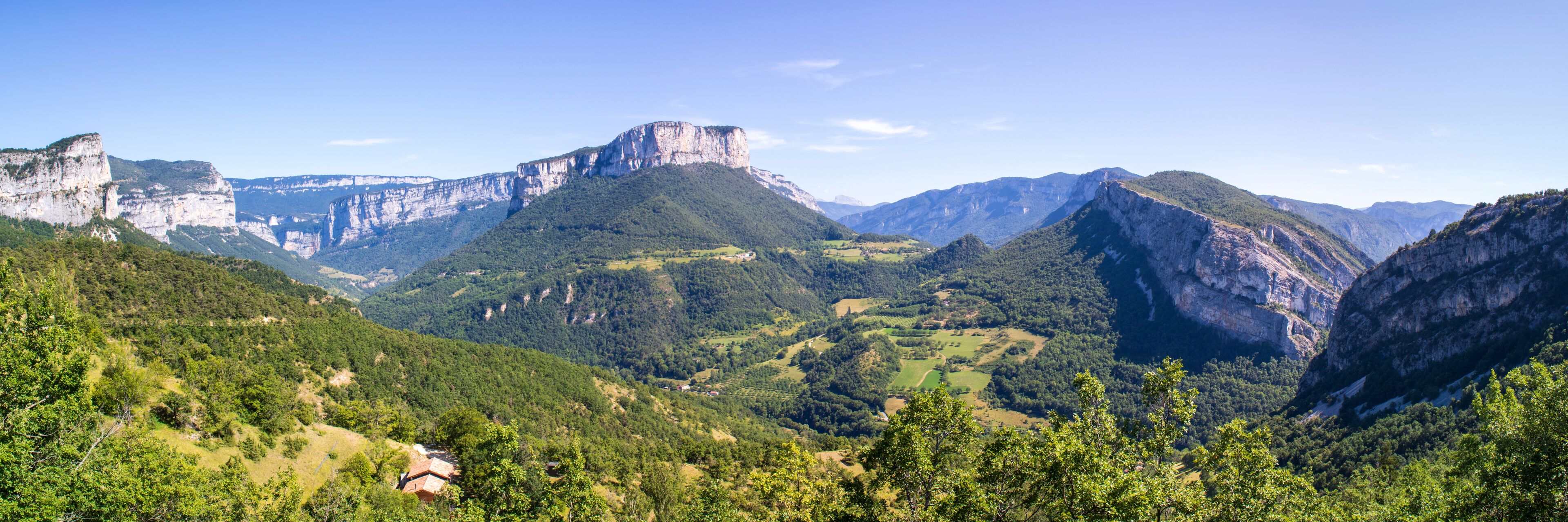 A mountainous landscape with a prominent cliff face and lush greenery.