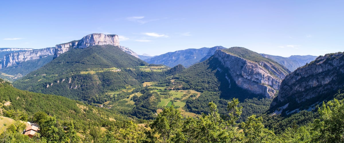 A mountainous landscape with a prominent cliff face and lush greenery.