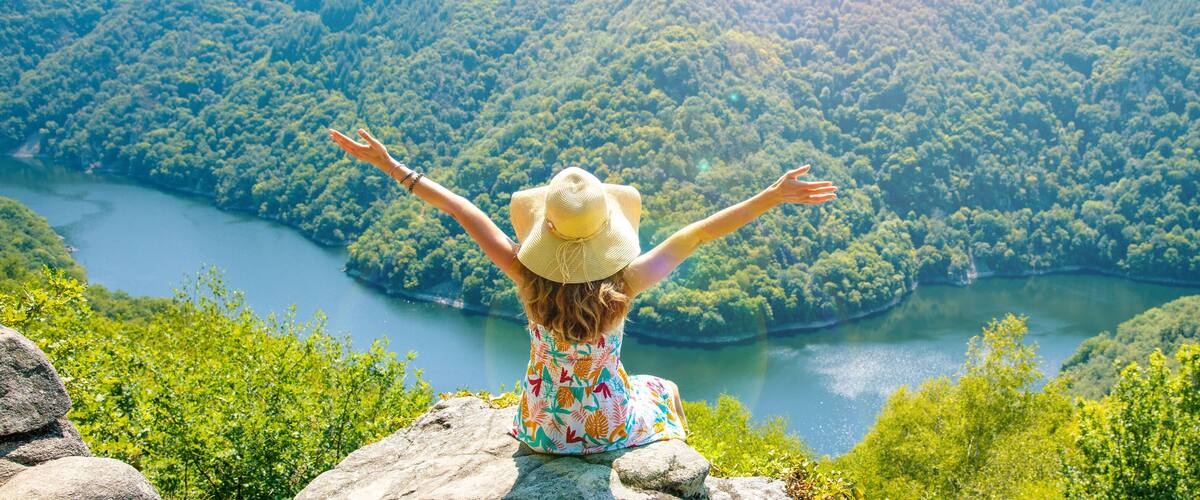 woman sitting on the mountain peak and amazing view of dordogne river and forest