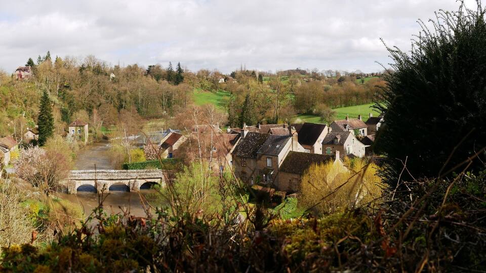 A historic village with stone houses, a bridge, and a river.
