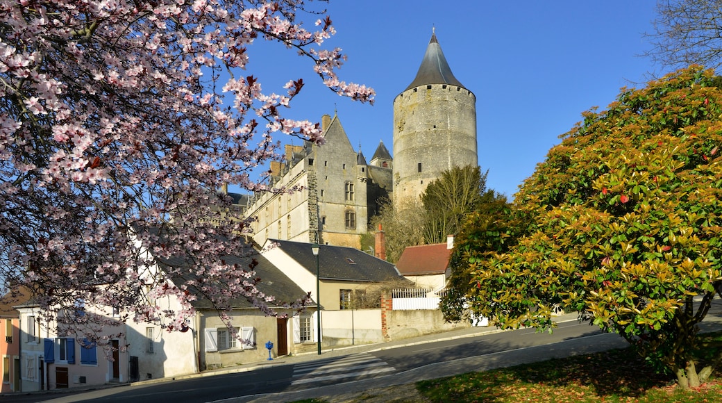 Un bâtiment historique doté d’une tour, entouré de cerisiers en fleurs et surplombé d’un ciel bleu azur.