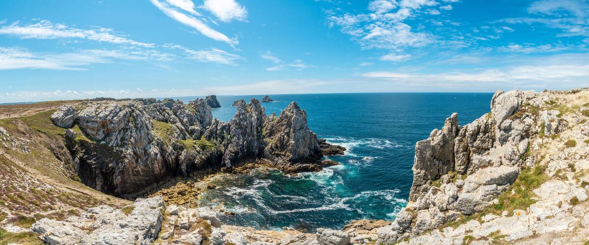 A coastal landscape with rocky cliffs, a sea view, and a tall stone monument.